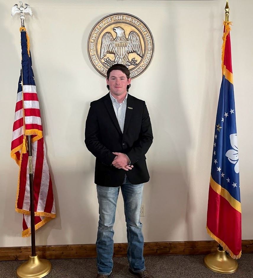Man in front of state seal and flag